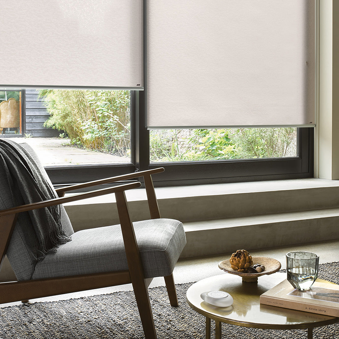 Modern living room with a gray armchair, small round table, and window blinds.